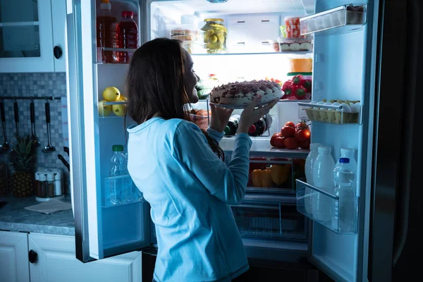 Sorrindo Jovem Mulher Olhando Para Bolo Frente Refrigerador Aberto — Fotografia de Stock