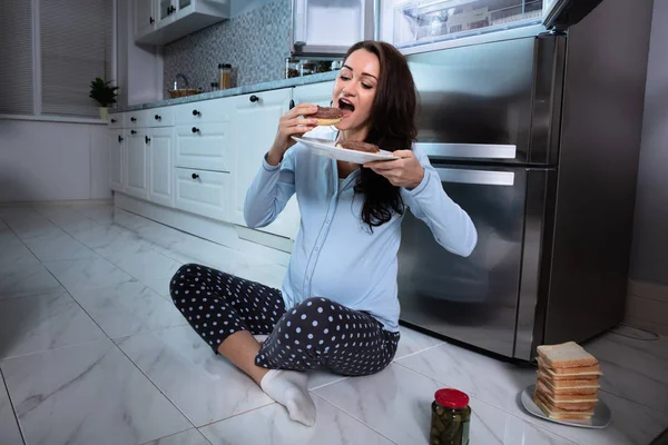Young Pregnant Woman Sitting Tiled Floor Eating Donut Kitchen — Stock Photo, Image
