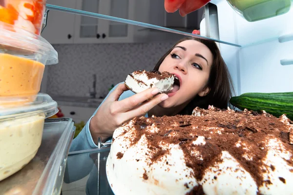 冷蔵庫からケーキのスライスを食べる若い女性 — ストック写真