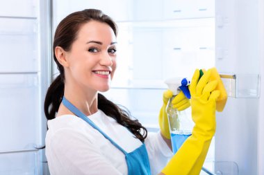 Arkadan Görünüş giyen genç bir kadın temizlik buzdolabı sünger ile eldiven