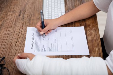 İşkadını beyaz bandaj el ahşap masa üzerinde çalışma yaralanma talep formu doldurma ile yakın çekim