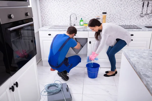 Jovem Mulher Limpeza Chão Enquanto Encanador Masculino Reparar Tubo Pia — Fotografia de Stock