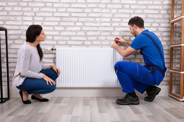 Mulher Bonita Olhando Para Jovem Encanador Masculino Uniforme Instalando Radiador — Fotografia de Stock