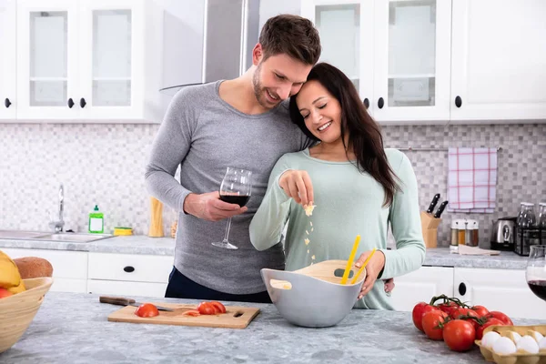 Smiling Wife Sprinkling Butter Her Husband Standing Kitchen Holding Wine — Stock Photo, Image