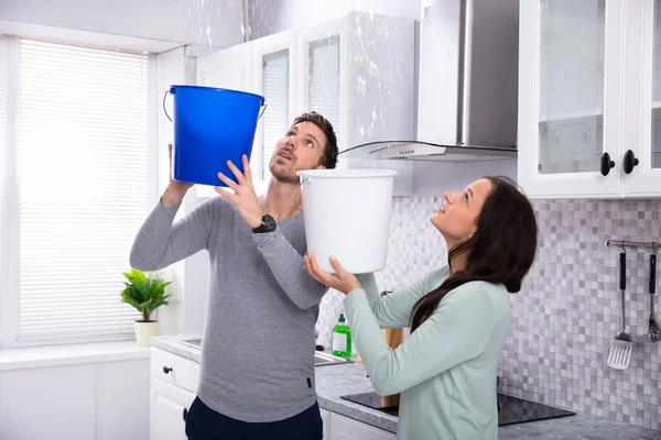 Close Worried Young Couple Collecting Water Leaking Ceiling Blue Bucket — Stock Photo, Image