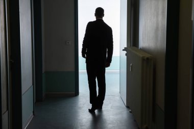 Açık kapı önünde duran bir işadamı arkadan görünüş