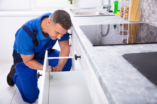 Close-up Of A Male Handyman Installing Door Of Drawer In The Kitchen