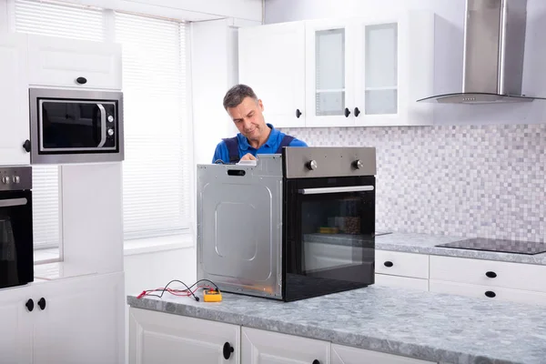 Rijpere Man Technicus Repareren Van Oven Keuken Werkblad — Stockfoto