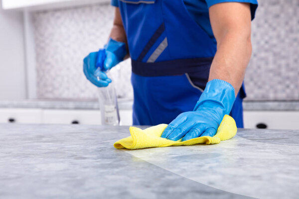 Средняя часть мужского уборщика уборщик грязный кухонный прилавок со спреем бутылки и салфетки
