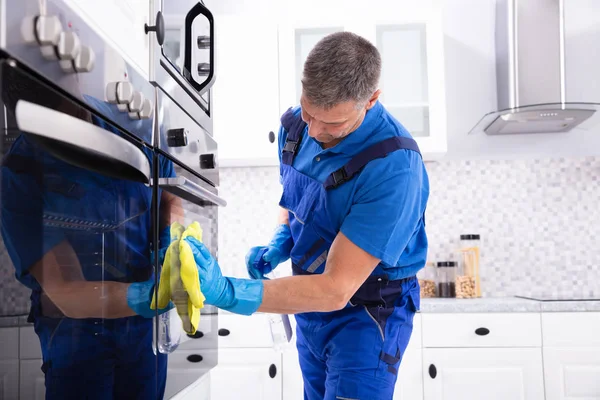 Close Homem Sorridente Faxineiro Forno Limpeza Com Guardanapo Amarelo Cozinha — Fotografia de Stock