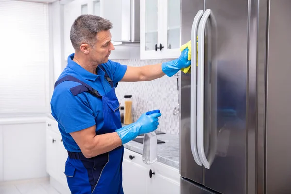 Male Janitor Cleaning Refrigerator Yellow Napkin Spray Detergent — Stock Photo, Image
