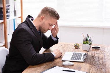 Ofiste çalışırken baş ağrısı çeken genç adam