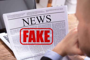 Man Reading Fake News In Newspaper Over Desk clipart