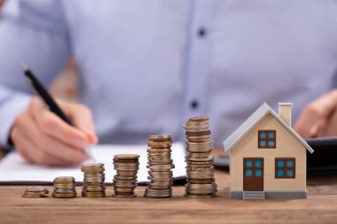 Sikke ve ev Model ahşap masanın üzerinde çalışan işadamı önünde masa üzerine yığılmış