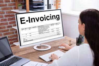 Close-up Of A Businesswoman Preparing E-invoicing Bill On Computer Over Wooden Desk clipart