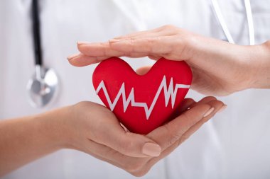 Beyaz ile kırmızı kalp şekli korumak erkek doktor el close-up darbe yendi