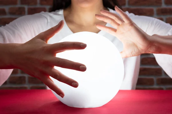 Närbild Fortuneteller Hand Täcker Den Glödande Crystal Ball Rött Skrivbord — Stockfoto