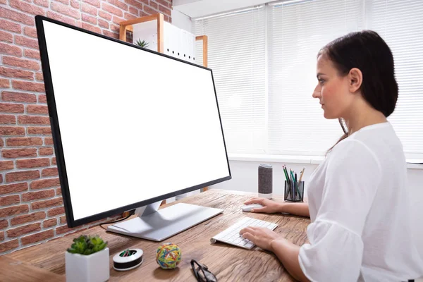 一个女商人在木桌上看着白色电脑屏幕的特写镜头 — 图库照片