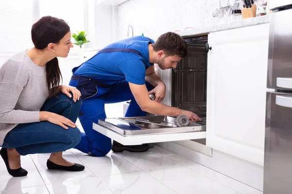Jovem Mulher Olhando Reparador Reparação Máquina Lavar Louça Cozinha — Fotografia de Stock