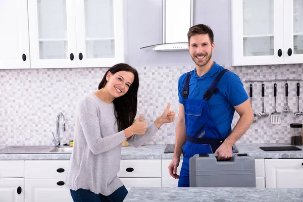 Usměvavá Mladá Žena Stojící Opravářem Ukazuje Palec Nahoru Znamení Kuchyni — Stock fotografie