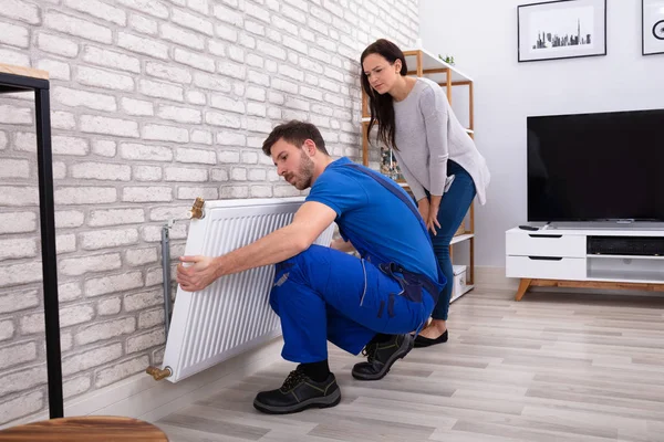 Jovem Reparador Instalando Radiador Parede Tijolo Com Mulher Casa — Fotografia de Stock