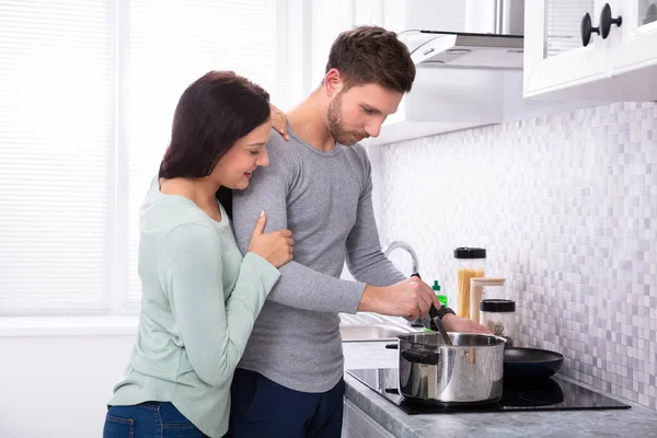 Jonge Man Maakt Eten Met Zijn Lachende Vrouw Staande Keuken — Stockfoto