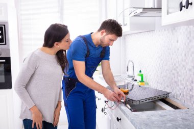 Erkek tamirci mutfakta duran kadın ile indüksiyon Ocak yükleme