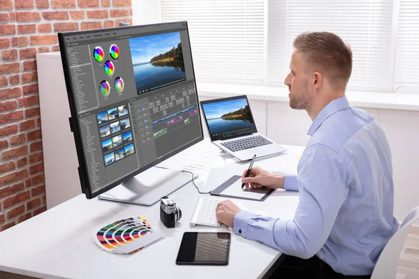 Male Editor Editing Video On Computer Over Wooden Desk