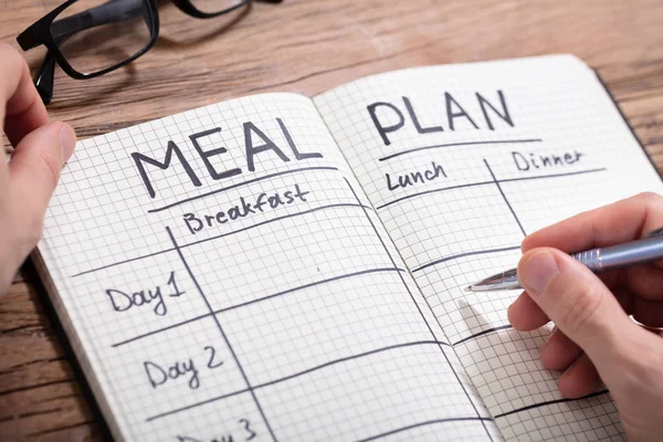 Close Human Hand Filling Meal Plan Checkered Pattern Notebook — Stock Photo, Image
