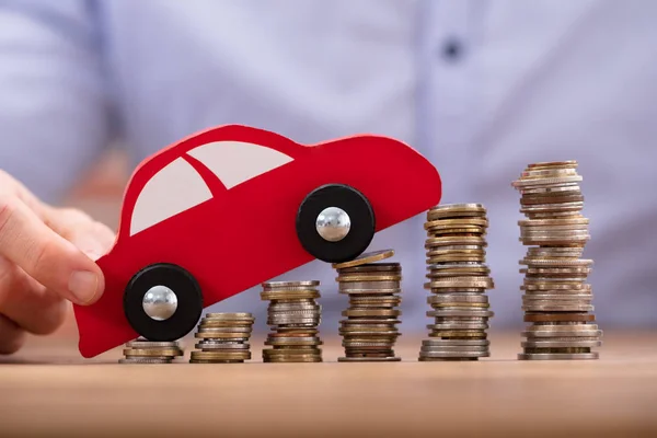 Close Mão Uma Pessoa Segurando Carro Sobre Moedas Empilhadas Douradas — Fotografia de Stock