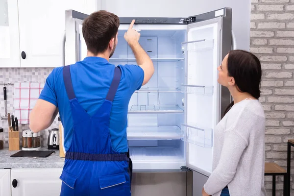 Junge Frau Schaut Männlichen Servicekräften Der Die Temperatur Des Kühlschranks — Stockfoto