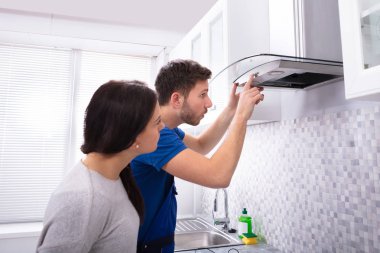 Genç ve güzel kadın üzerinde mutfak mutfak aspiratör filtre tamir tamirci bakarak karşı