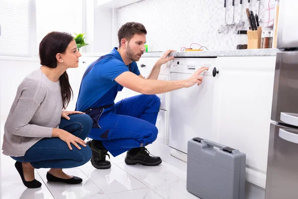 Serviceman Crouching Kitchen Floor Pressing Button Dishwasher While Woman Looking — Stock Photo, Image