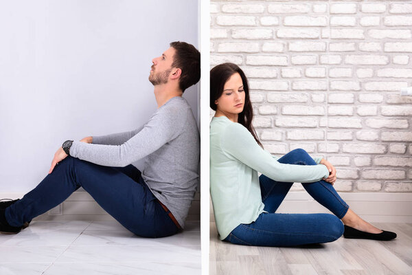 Sad Young Couple Sitting Back To Back On Floor At Home