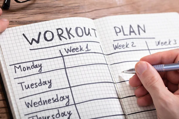 Close-up Of A Person's Hand Writing Workout Plan In Checkered Pattern Notebook — Stock Image Close Person Hand Writing Workout Plan Checkered Pattern Notebook Stock Image