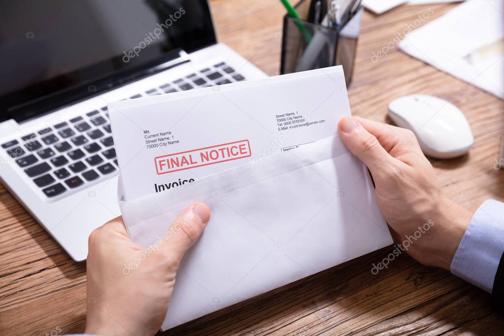 Close-up Of A Person's Hand Opening The Envelope With Final Notice Invoice In It