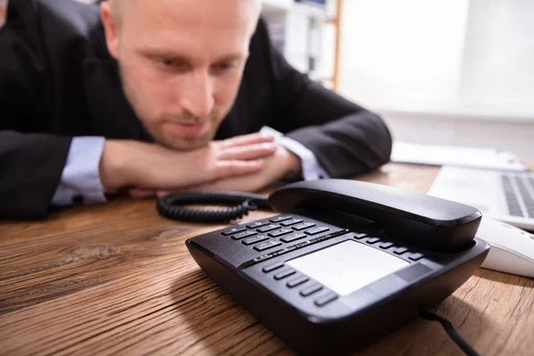 Smiling Young Businessman Waiting For A Call On Landline