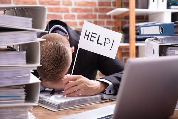 Unhappy Businessman Holding White Help Flag In Office