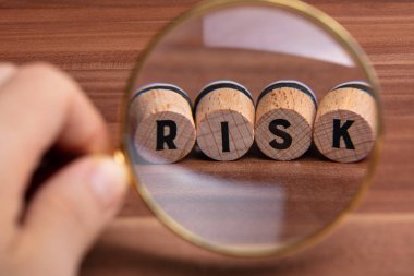 Ahşap masanın üstündeki mantar üzerindeki Risk Sözcüğünü İncelemek İçin İnsan Elinin Yakın Çekimi