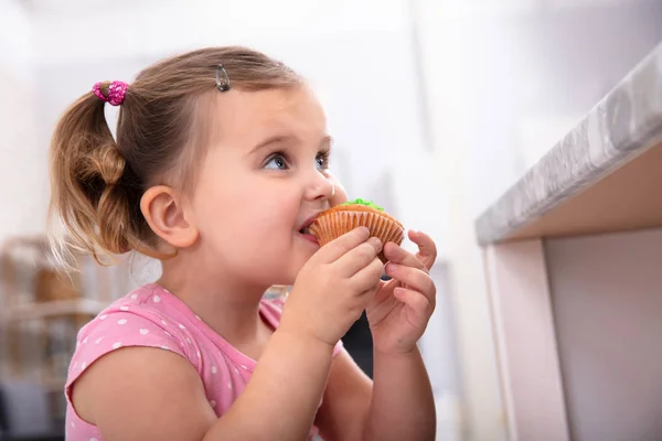 Aranyos Éhes Lány Vesz Egy Falatot Finom Cupcake Konyhában — Stock Fotó