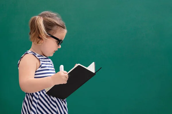 Cute Little Girl Standing Front Chalkboard Reading Book — стоковое фото
