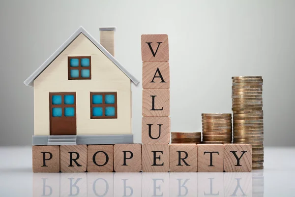 Hausmodell Und Gestapelte Münzen Mit Immobilienwertkonzept Auf Reflektierendem Schreibtisch — Stockfoto