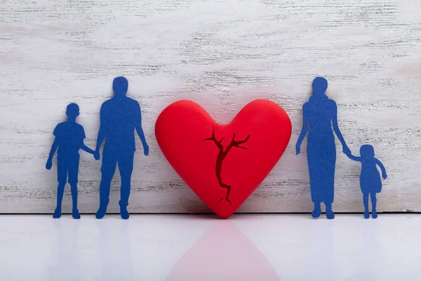 Broken Heart Between Cutout Blue Family Against White Textured Background