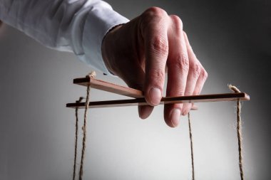 Bir Işadamı el Gri arka plan karşı dize Ile Marionette manipüle