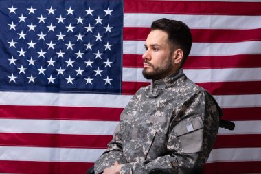 Bir Amerikan bayrağı önünde tekerlekli sandalyede oturan Veteran yan görünümü