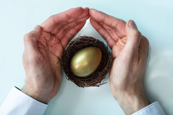 ビジネスマンの手が 巣に金色の卵を守っているのを見た — ストック写真