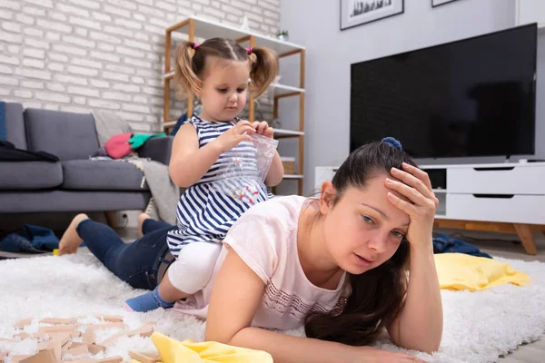 Happy Mischievous Girl Playing Her Tired Mother Lying Carpet — Stok Foto