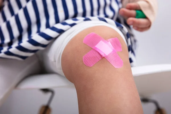 Close Joelho Menina Com Uma Bandagem Adesiva Rosa — Fotografia de Stock