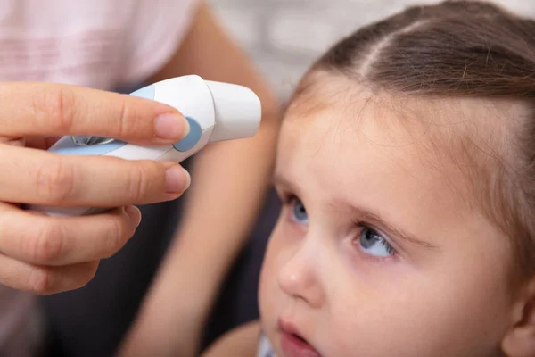 Mother Checking Fever Her Sick Daughter Using Forehead Thermometer Home — Stock Photo, Image