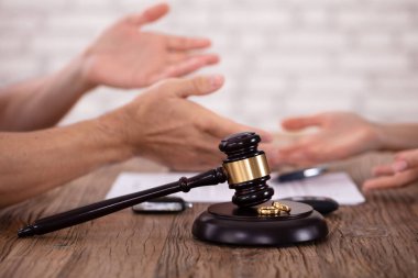 Ahşap masanın üzerinde altın yüzüklerle birbirleriyle tartışan çiftlerin yakın çekimi.